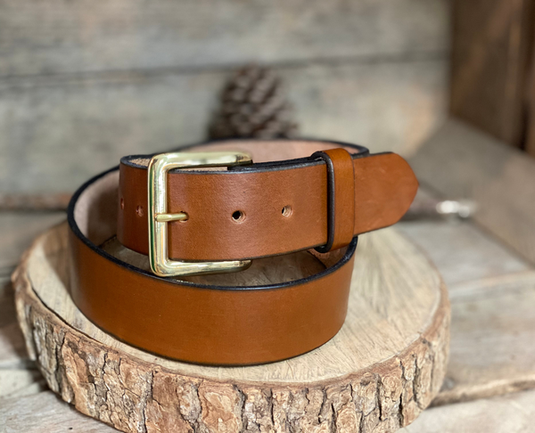 a brown leather belt sitting on top of a piece of wood